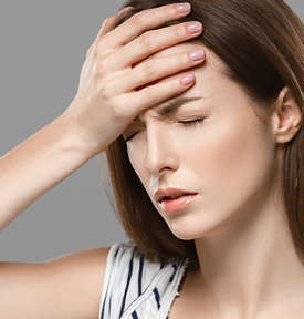 Woman feeling dizzy and sitting on bed