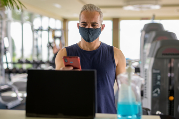 man wearing mask checking into the gym